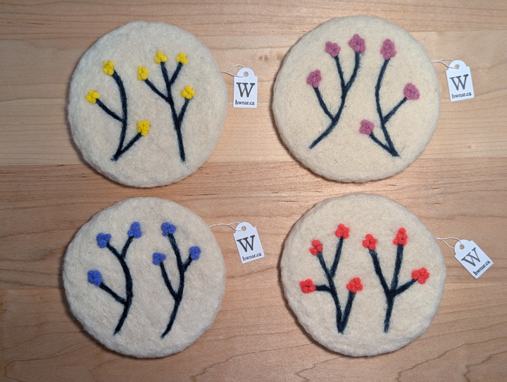 Felted circular white coasters with stylized floral designs.