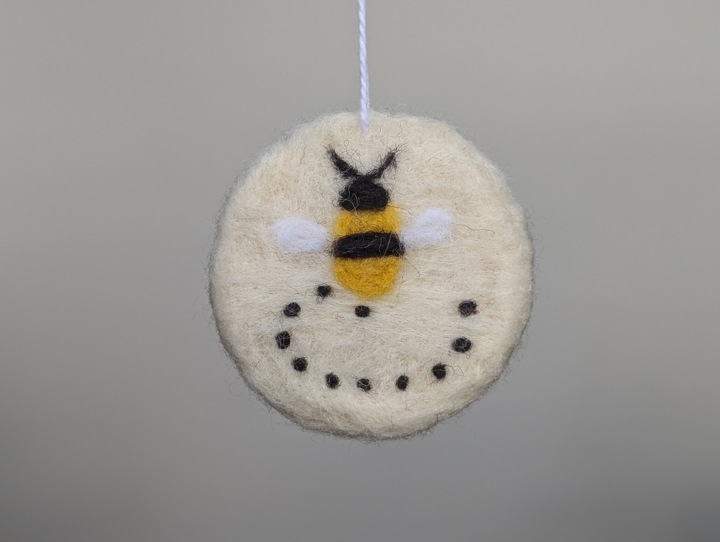 A round white decoration with a happy buzzing bee.