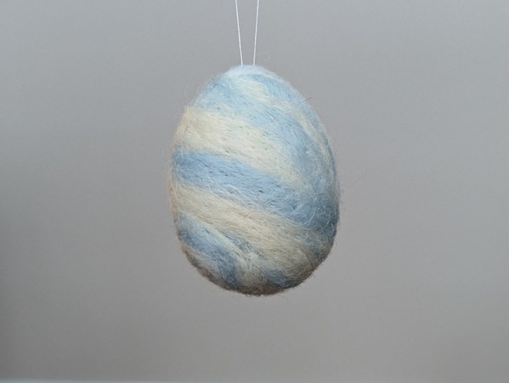 A felted egg decorated in a swirling blue and white design.