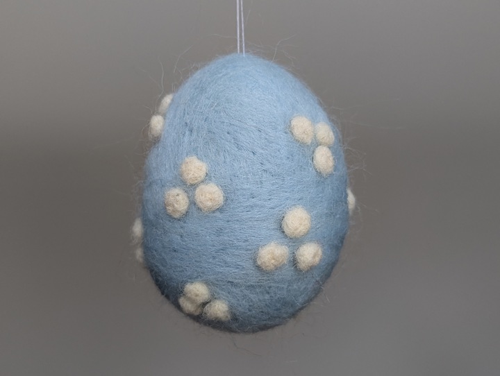 A felted sky blue egg with white polka dots.