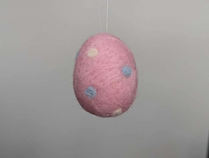 A small felted pink egg with white and baby blue polka dots.