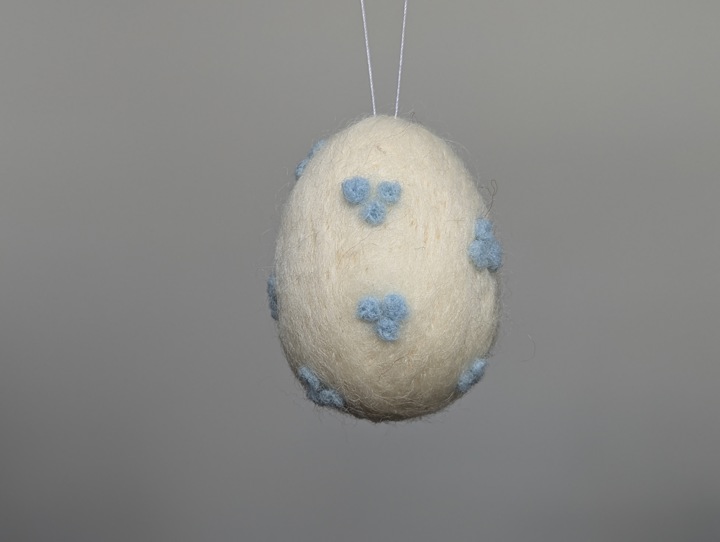 A small felted white egg with baby blue polka dots.