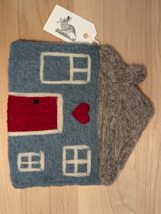 A felted country blue house with a heather grey roof and a red door with a heart motif above it.
