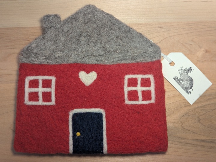 A felted red house with a heather grey roof and a hunter green door with a heart motif above it.