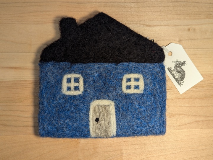 A felted blue house with a black roof and a heather grey door.