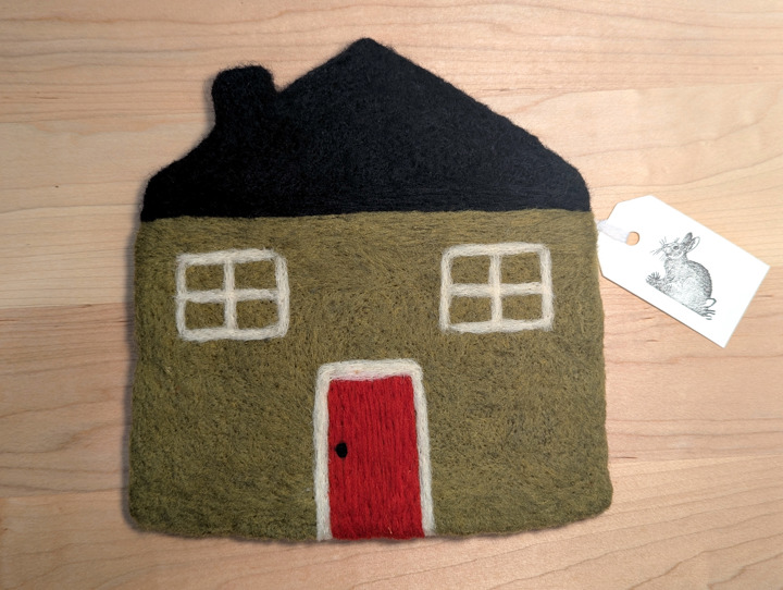 A felted olive green house with a black roof and red door.