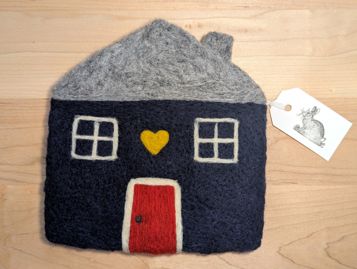 A felted navy blue house with a heather grey roof and a red door with a yellow heart motif above it.
