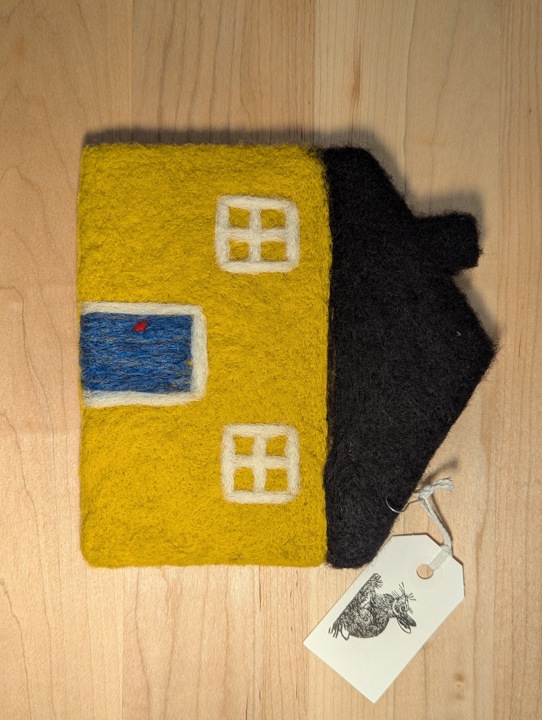 A felted yellow house with a black roof and a blue door.