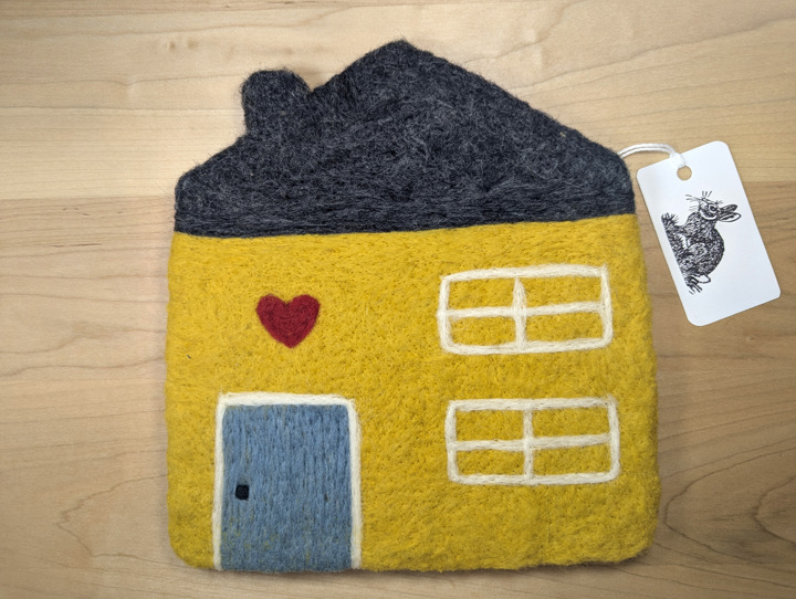 A felted yellow house with a brown roof and a country blue door with a heart motif above it.