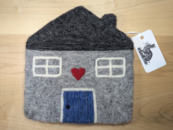 A felted grey house with a dark grey roof and a heather blue door with a heart motif above it.