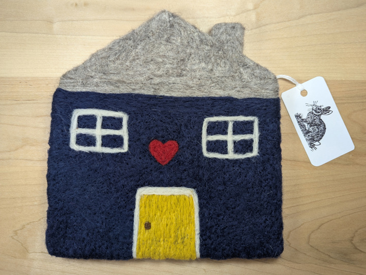 A felted navy blue house with a heather grey roof and a yellow door with a heart motif above it.