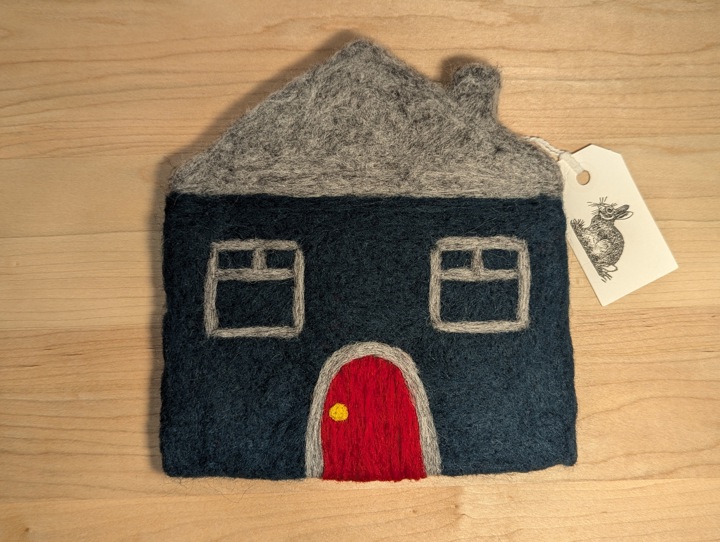 A felted hunter green house with a heather grey roof and a red door.