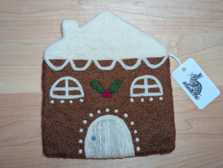 A felted gingerbread house with lashings of icing and a holly and ivy motif above the door.
