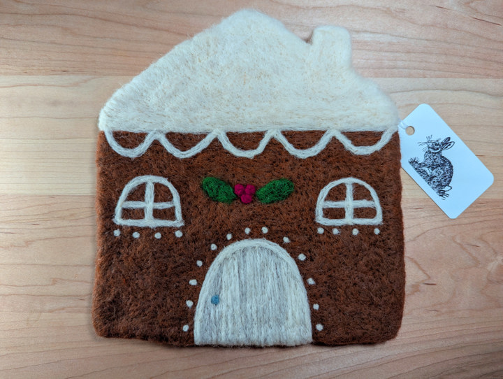 A felted gingerbread house with lashings of icing and a holly and ivy motif above the door.