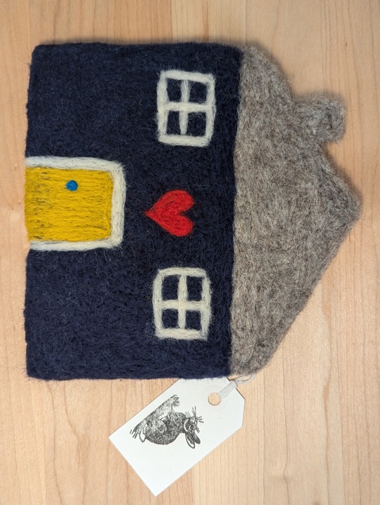 A felted navy blue house with a heather grey roof and a mustard yellow door with a heart motif above it.