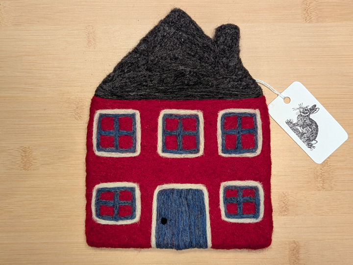 A felted red house with a dark grey roof, blue and white trim around the windows, and a blue door.