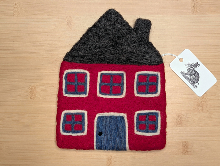 A felted red house with a dark grey roof, blue and white trim around the windows, and a blue door.