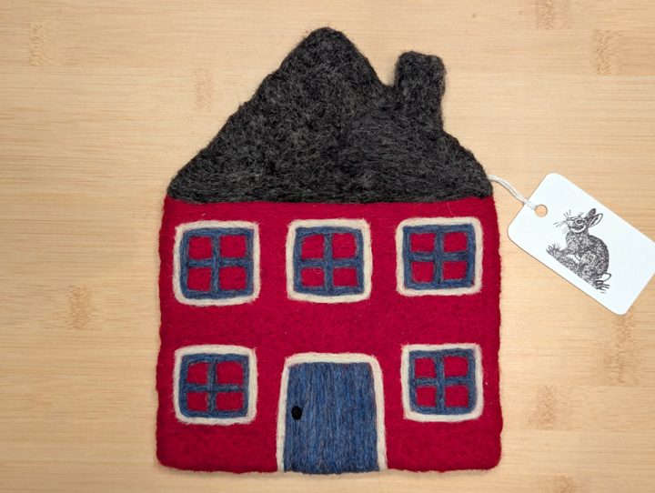 A felted red house with a dark grey roof, blue and white trim around the windows, and a blue door.
